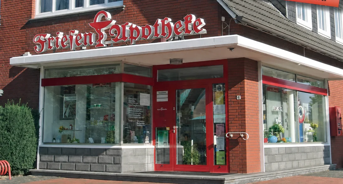 Ladenfront der Friesen-Apotheke in Großheide mit rot beschrifteter Schaufensterfront